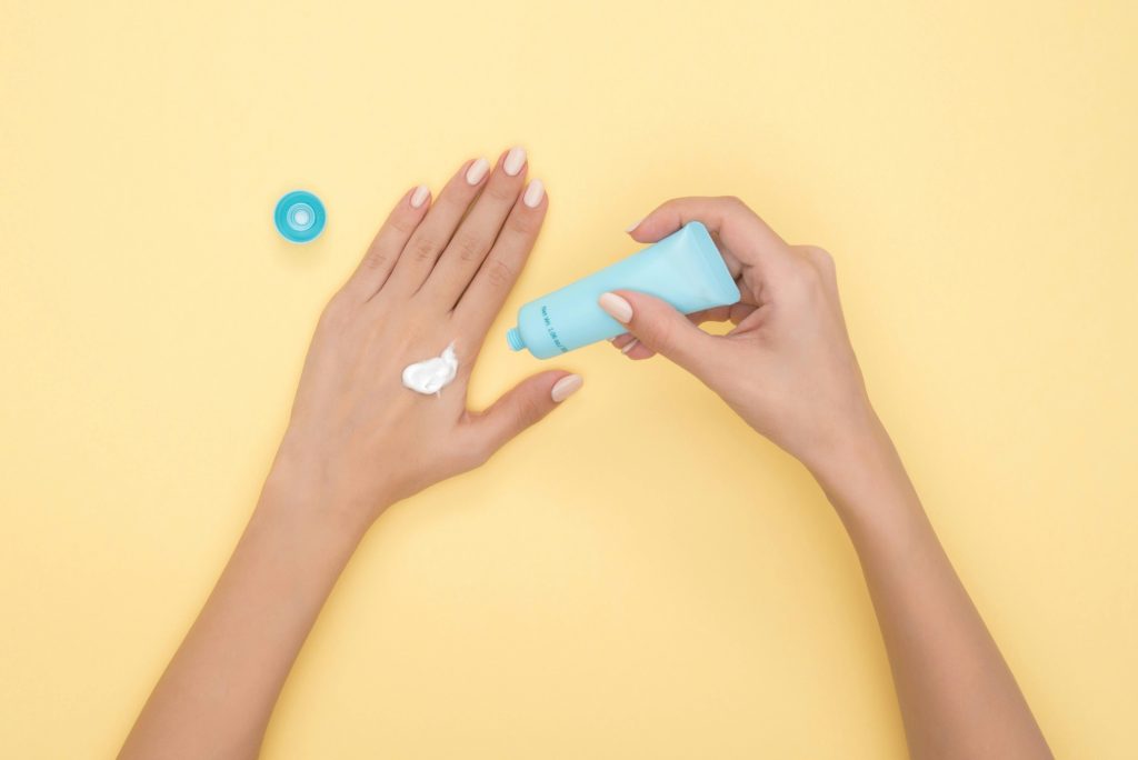 Person putting lotion on their skin
