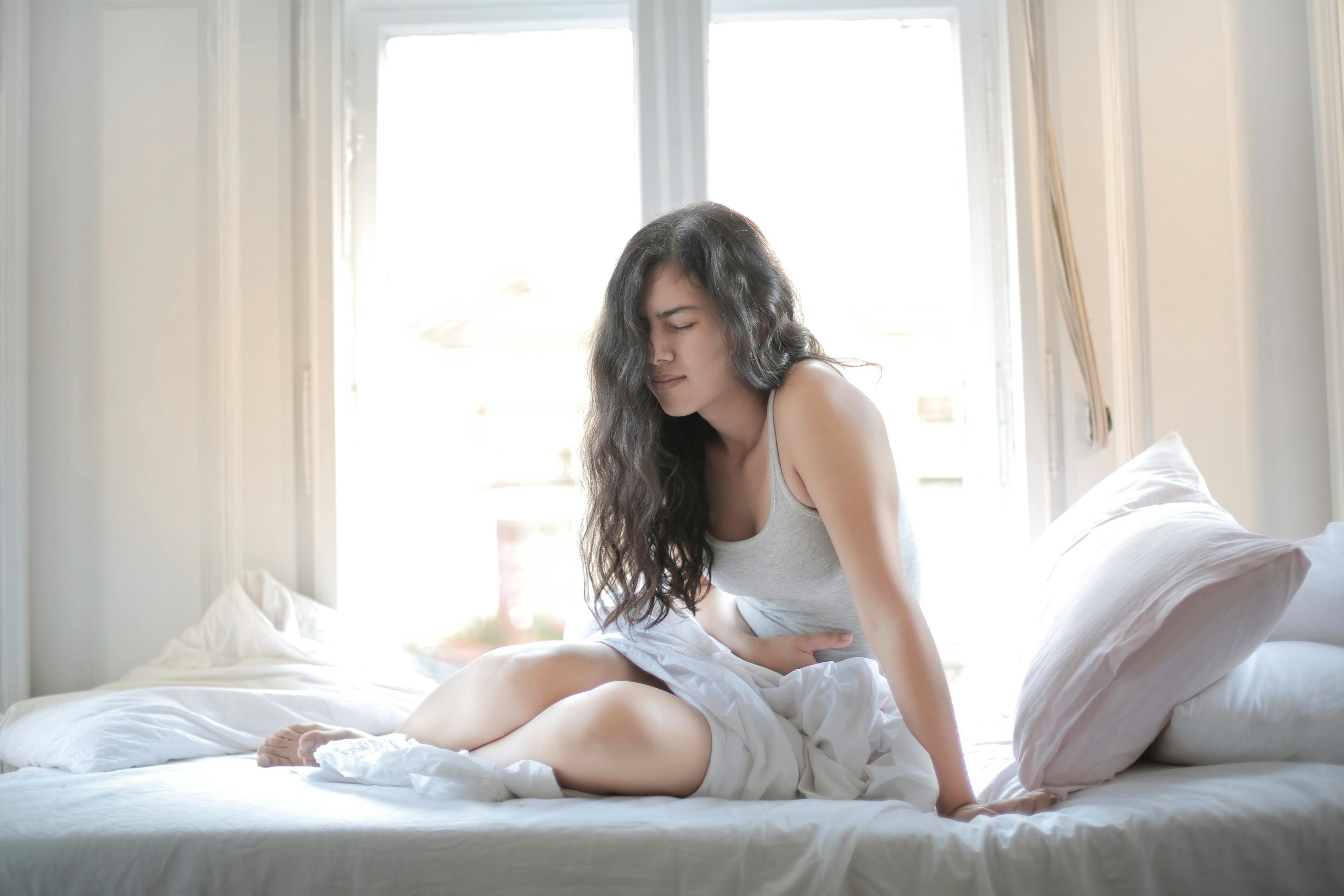 Woman in be holding her stomach in pain