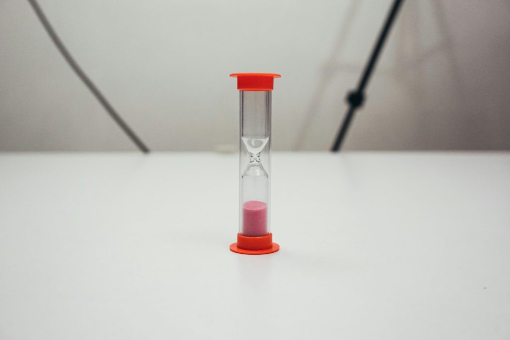 A small red hourglass sitting on a table